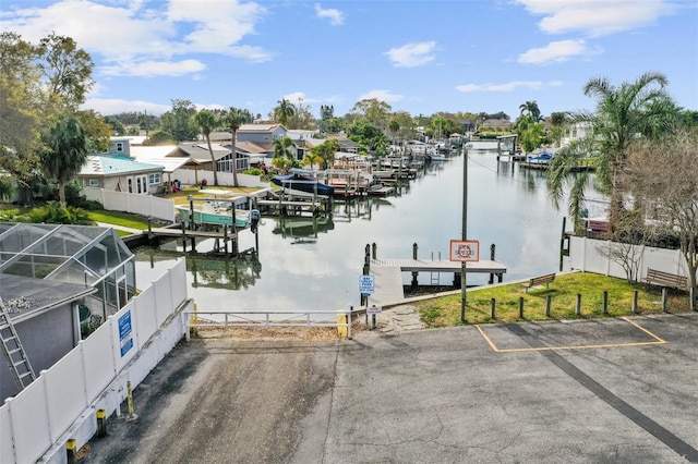 view of dock with a water view, fence, and a residential view