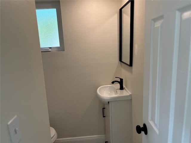 bathroom featuring toilet, vanity, and baseboards