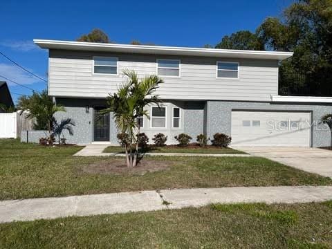 view of front of house with driveway, an attached garage, fence, and a front yard