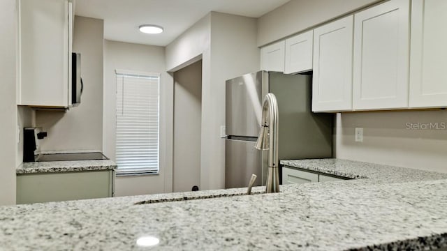 kitchen with light stone counters, stainless steel appliances, and white cabinetry