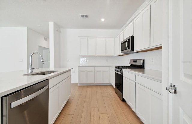 kitchen featuring white cabinetry, light wood-type flooring, appliances with stainless steel finishes, and sink