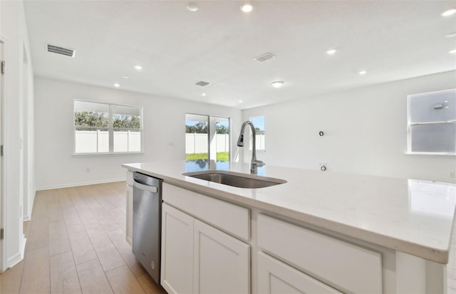 kitchen with white cabinets, sink, stainless steel dishwasher, light stone countertops, and light hardwood / wood-style flooring