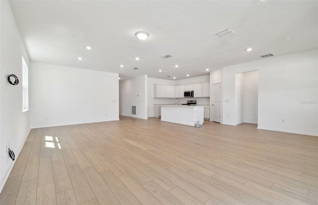 unfurnished living room featuring recessed lighting, baseboards, and light wood-type flooring