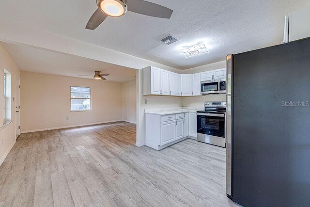 kitchen with ceiling fan, light wood-type flooring, stainless steel appliances, and white cabinets