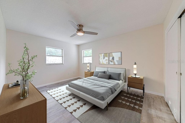 bedroom featuring ceiling fan, wood-type flooring, a textured ceiling, and a closet