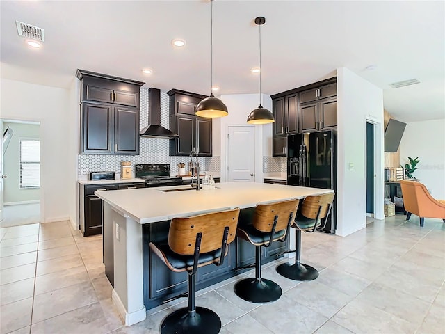 kitchen with wall chimney exhaust hood, black appliances, a sink, and visible vents