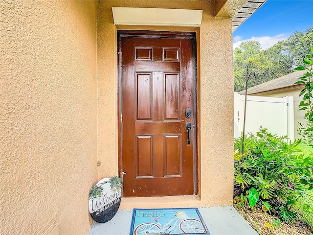 entrance to property with fence and stucco siding