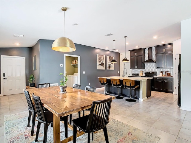 dining room with light tile patterned floors, washer and clothes dryer, visible vents, and baseboards