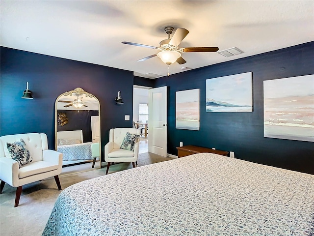 bedroom with an accent wall, visible vents, ceiling fan, and carpet flooring