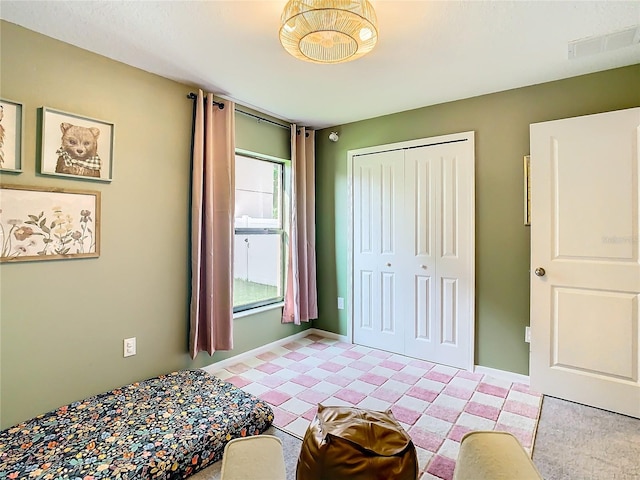 bedroom with light floors, baseboards, visible vents, and a closet