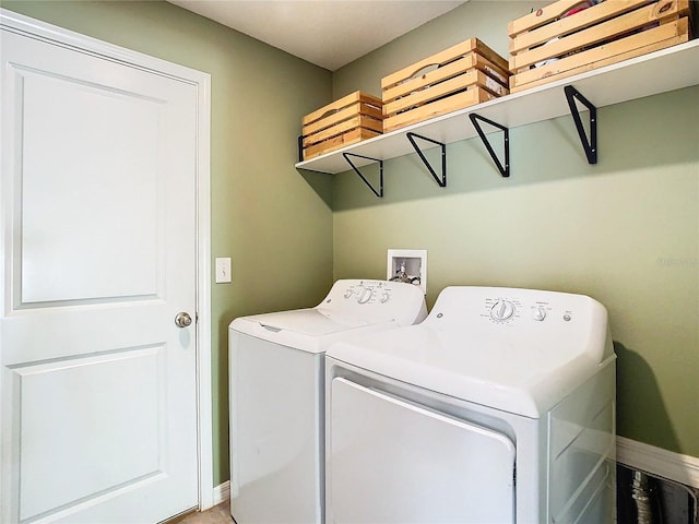 washroom with laundry area, separate washer and dryer, and baseboards