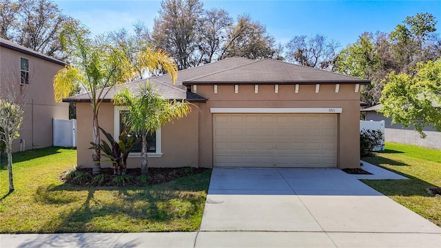 view of front of property with driveway, a garage, fence, a front yard, and stucco siding