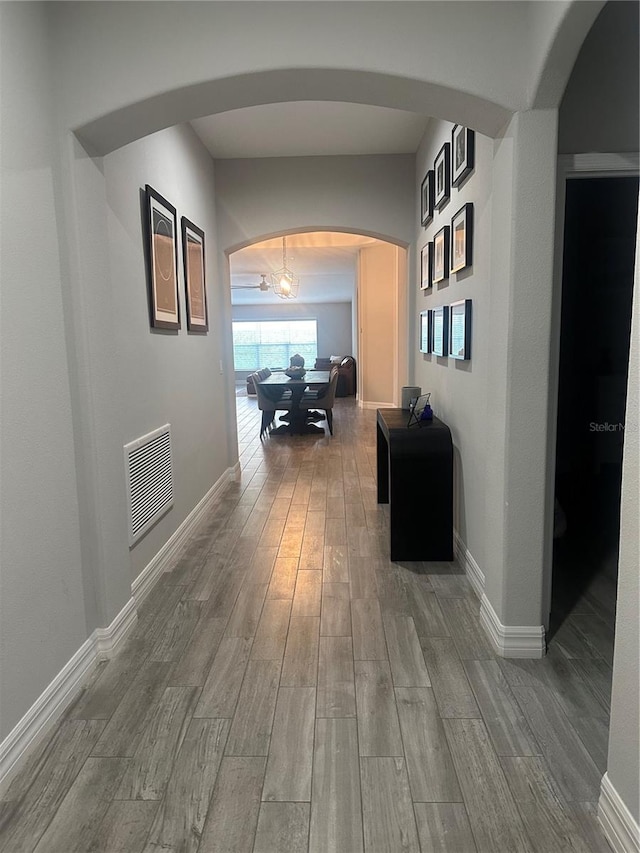 hall featuring hardwood / wood-style floors and a chandelier