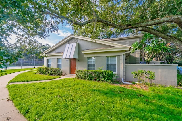 view of front of home with fence, a front lawn, and stucco siding