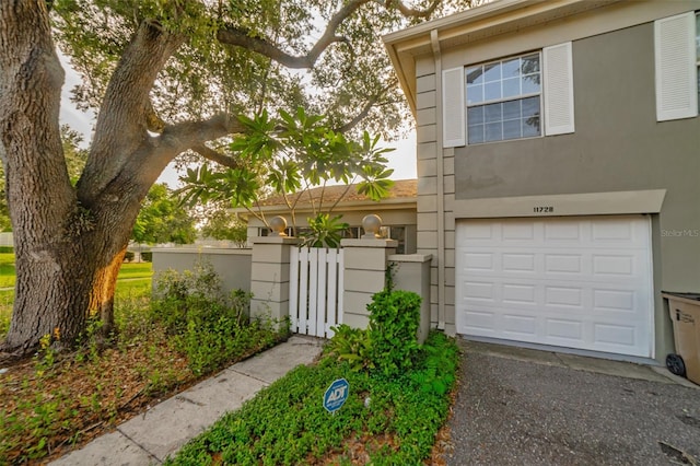 view of front of house with a garage, a gate, driveway, and stucco siding