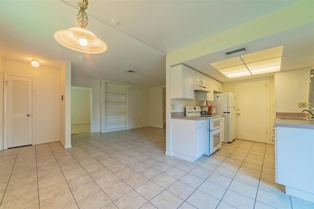 kitchen featuring white appliances, light tile patterned flooring, sink, white cabinets, and decorative light fixtures