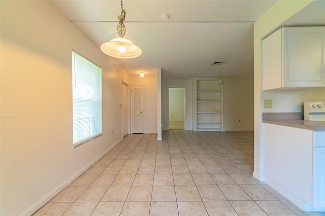 spare room with light tile patterned floors, visible vents, baseboards, and built in features