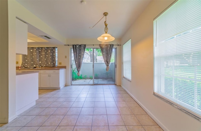 unfurnished dining area featuring baseboards, visible vents, and light tile patterned flooring