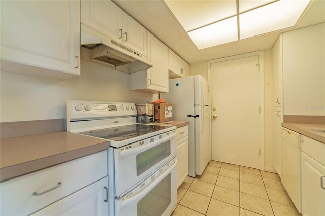 kitchen featuring light tile patterned flooring, white appliances, and white cabinetry