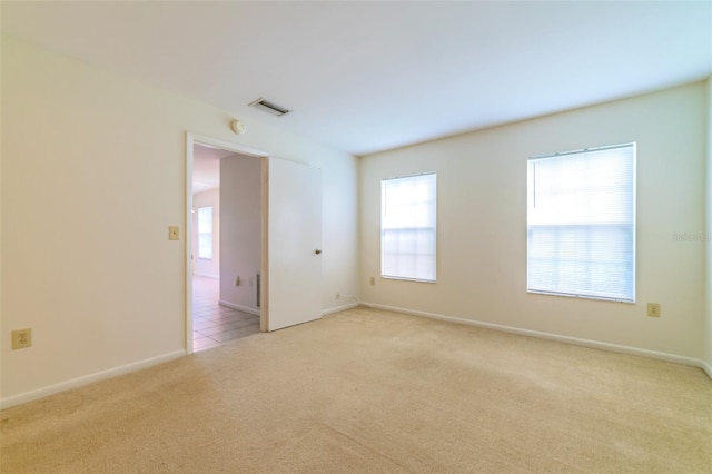 spare room with visible vents, light carpet, and baseboards