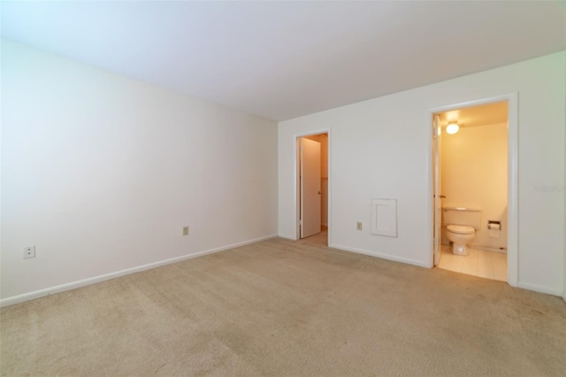 unfurnished bedroom featuring light carpet and ensuite bathroom