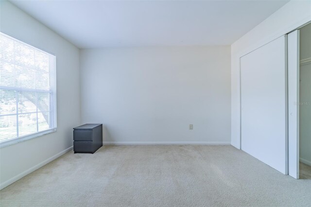 unfurnished bedroom featuring a closet and light colored carpet