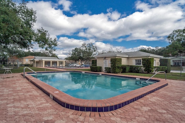 community pool with a patio area and fence