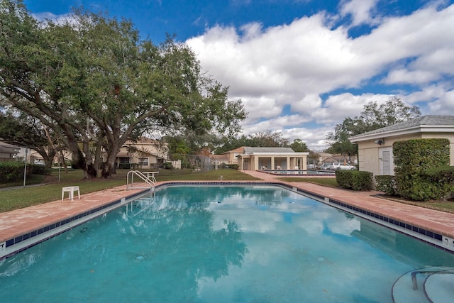 outdoor pool with an outbuilding, a patio, a yard, and fence