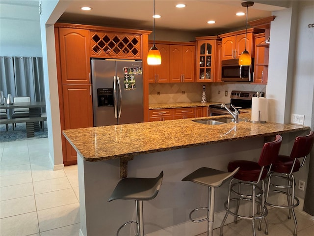 kitchen with backsplash, pendant lighting, appliances with stainless steel finishes, kitchen peninsula, and light tile patterned flooring