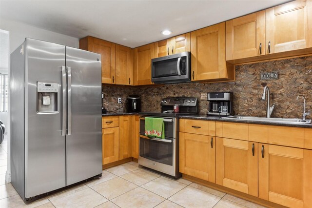 kitchen featuring backsplash, appliances with stainless steel finishes, sink, dark stone countertops, and light tile patterned flooring