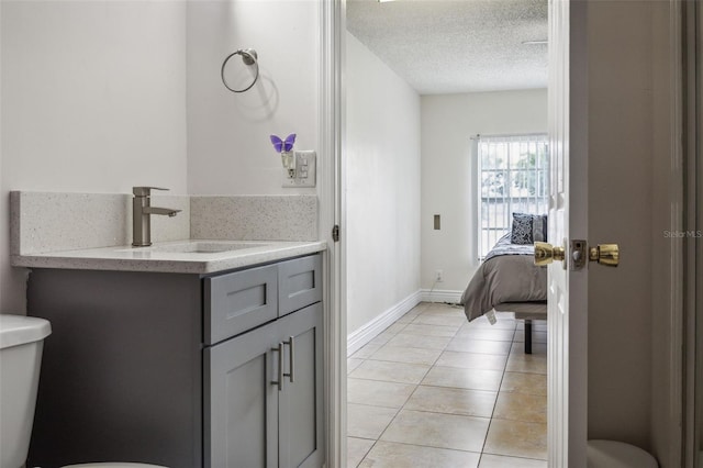 half bathroom featuring toilet, tile patterned flooring, a textured ceiling, and vanity