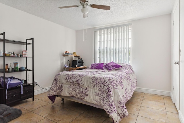 bedroom featuring a textured ceiling, ceiling fan, tile patterned flooring, and baseboards