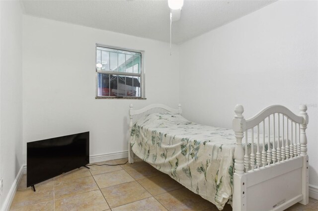 bedroom featuring ceiling fan, light tile patterned flooring, and a textured ceiling