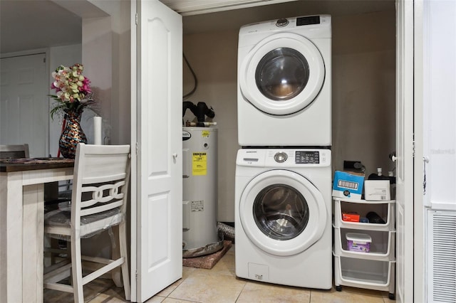 clothes washing area with stacked washer and dryer, light tile patterned floors, laundry area, and electric water heater