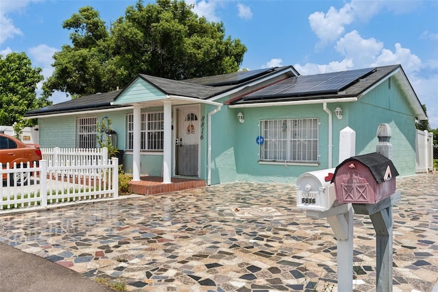 view of front facade featuring fence and roof mounted solar panels