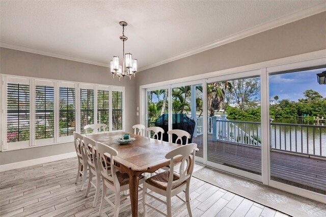 210 Lakeview Dr, Anna Maria, FL 34216 - dining space featuring a water view, light wood-type flooring, a chandelier, and crown molding