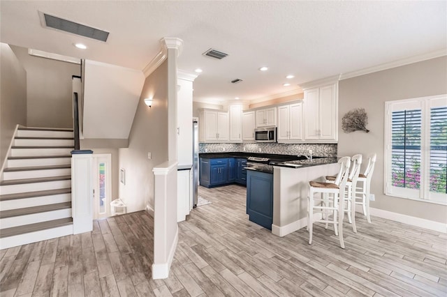 210 Lakeview Dr, Anna Maria, FL 34216 - kitchen with a peninsula, blue cabinets, appliances with stainless steel finishes, and visible vents