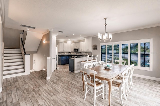 210 Lakeview Dr, Anna Maria, FL 34216 - dining room featuring visible vents, ornamental molding, light wood-type flooring, and a chandelier