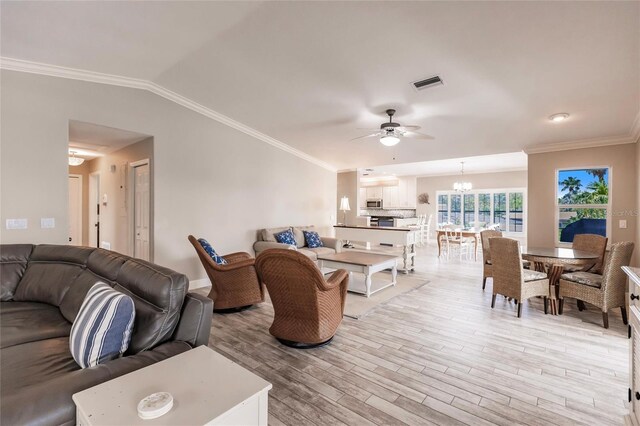210 Lakeview Dr, Anna Maria, FL 34216 - living room featuring light wood-style flooring, visible vents, crown molding, lofted ceiling, and ceiling fan with notable chandelier