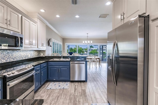 210 Lakeview Dr, Anna Maria, FL 34216 - kitchen featuring a notable chandelier, a sink, appliances with stainless steel finishes, a peninsula, and blue cabinetry