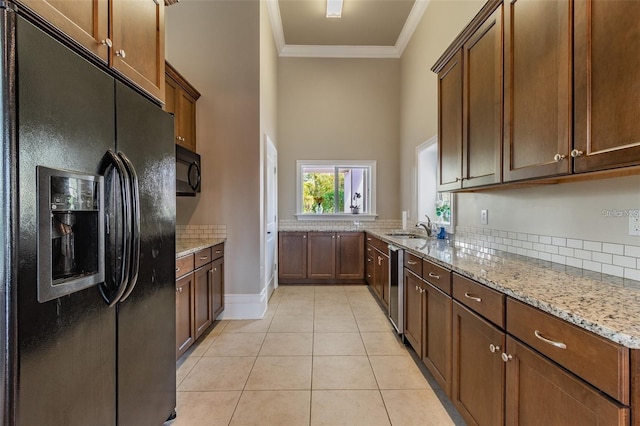 kitchen with sink, light stone counters, light tile patterned floors, black appliances, and ornamental molding