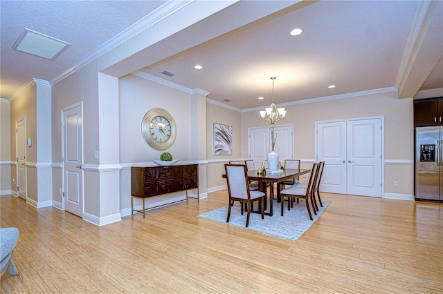 dining area featuring light hardwood / wood-style floors, an inviting chandelier, and crown molding