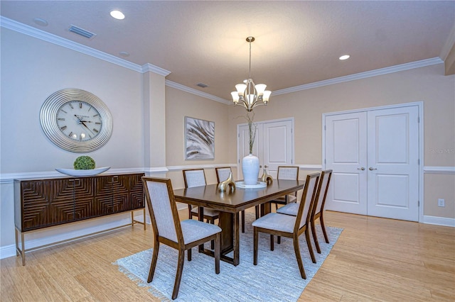 dining space with crown molding, light hardwood / wood-style floors, and a notable chandelier