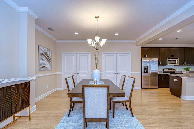 dining space featuring light hardwood / wood-style flooring, an inviting chandelier, and crown molding