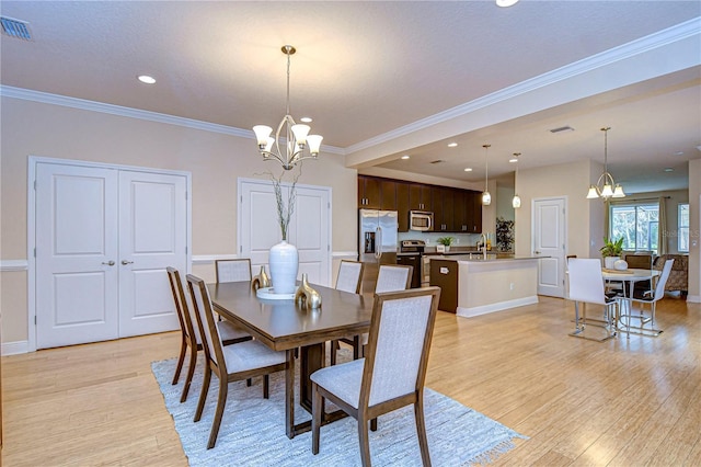 dining room with sink, light wood-type flooring, crown molding, and a chandelier