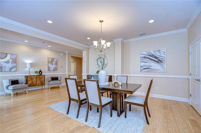 dining room with a notable chandelier, ornamental molding, and light hardwood / wood-style flooring