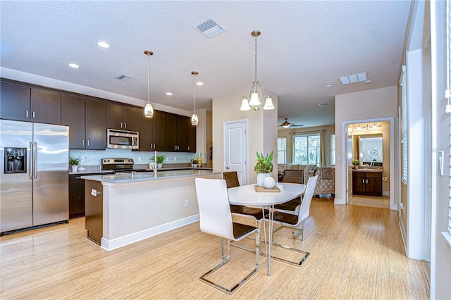 kitchen featuring dark brown cabinetry, pendant lighting, stainless steel appliances, and ceiling fan with notable chandelier