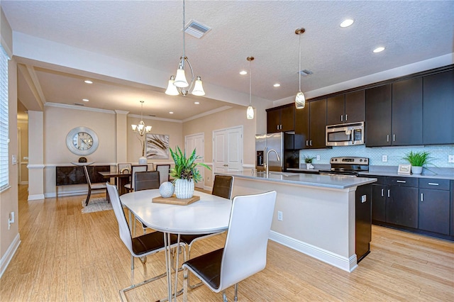 kitchen featuring decorative light fixtures, an island with sink, appliances with stainless steel finishes, tasteful backsplash, and a notable chandelier