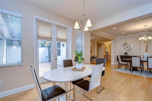 dining space featuring a notable chandelier, ornamental molding, and light hardwood / wood-style flooring