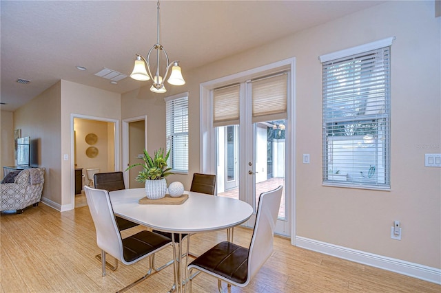 dining space with light wood-type flooring, a wealth of natural light, and a chandelier